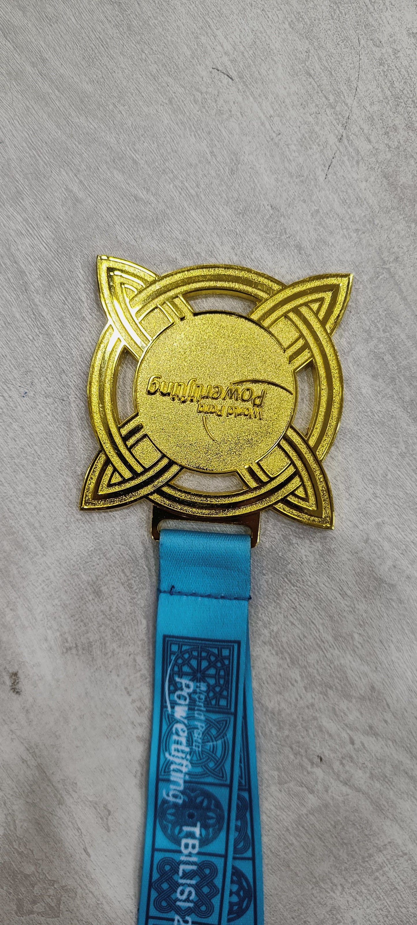 Gold powerlifting medal with teal lanyard from Tbilisi 2017.