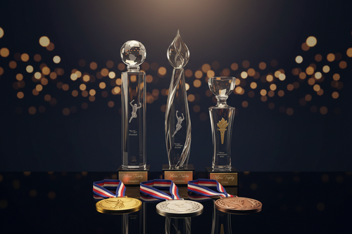 A premium set of gold silver bronze medals and custom crystal trophies displayed for a sports recognition award ceremony.
