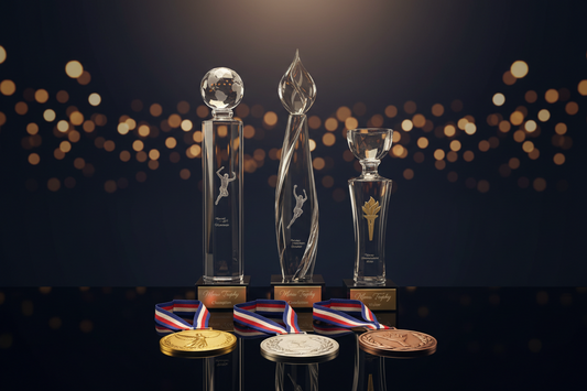 A premium set of gold silver bronze medals and custom crystal trophies displayed for a sports recognition award ceremony.