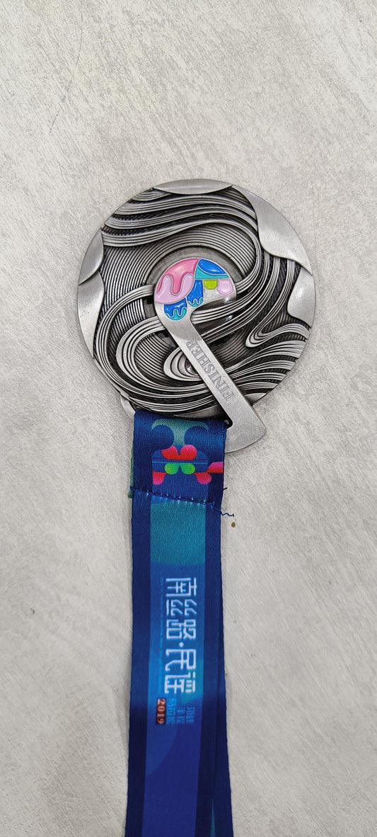 Image of a silver and blue custom finisher medal with a lanyard.
