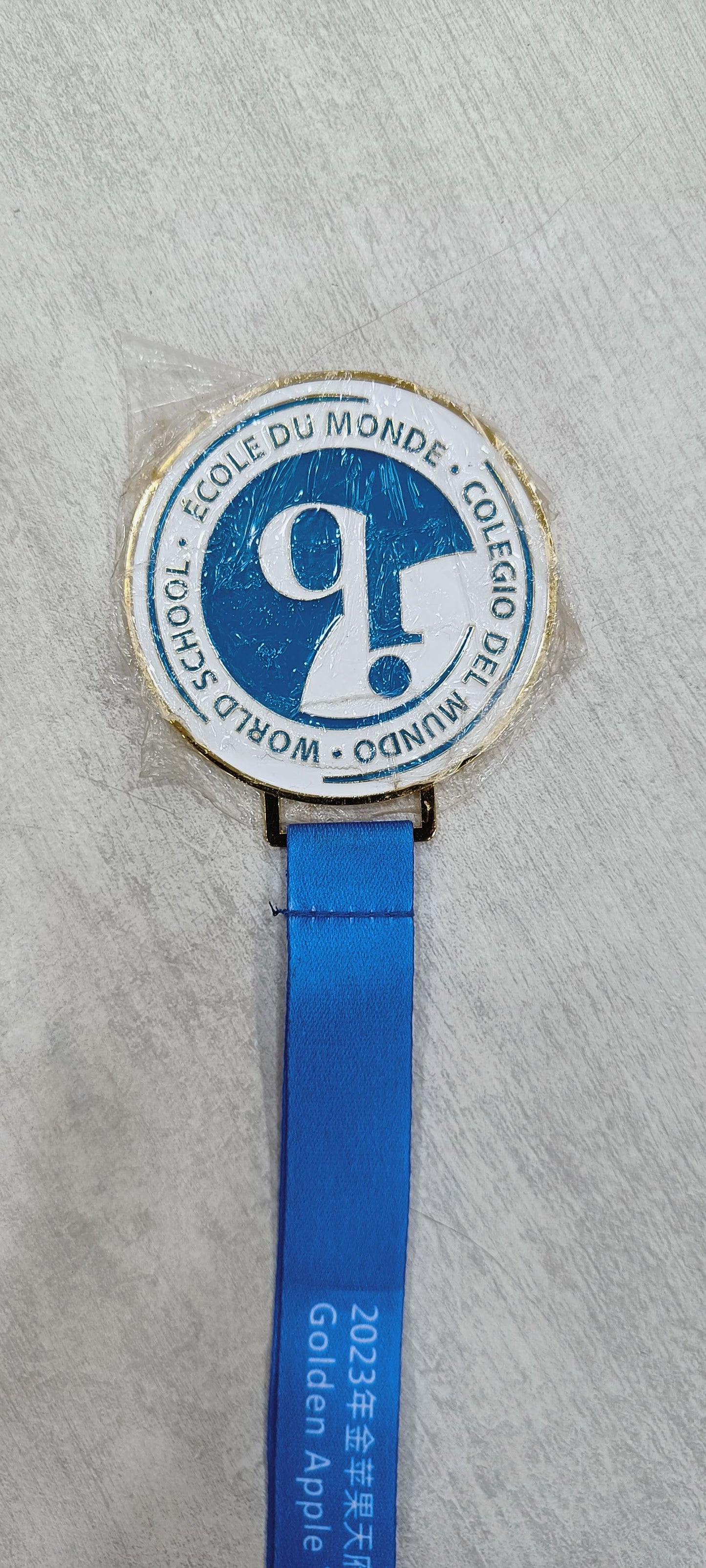 Gold and blue custom award medal with ribbon for 2023 Golden Apple.